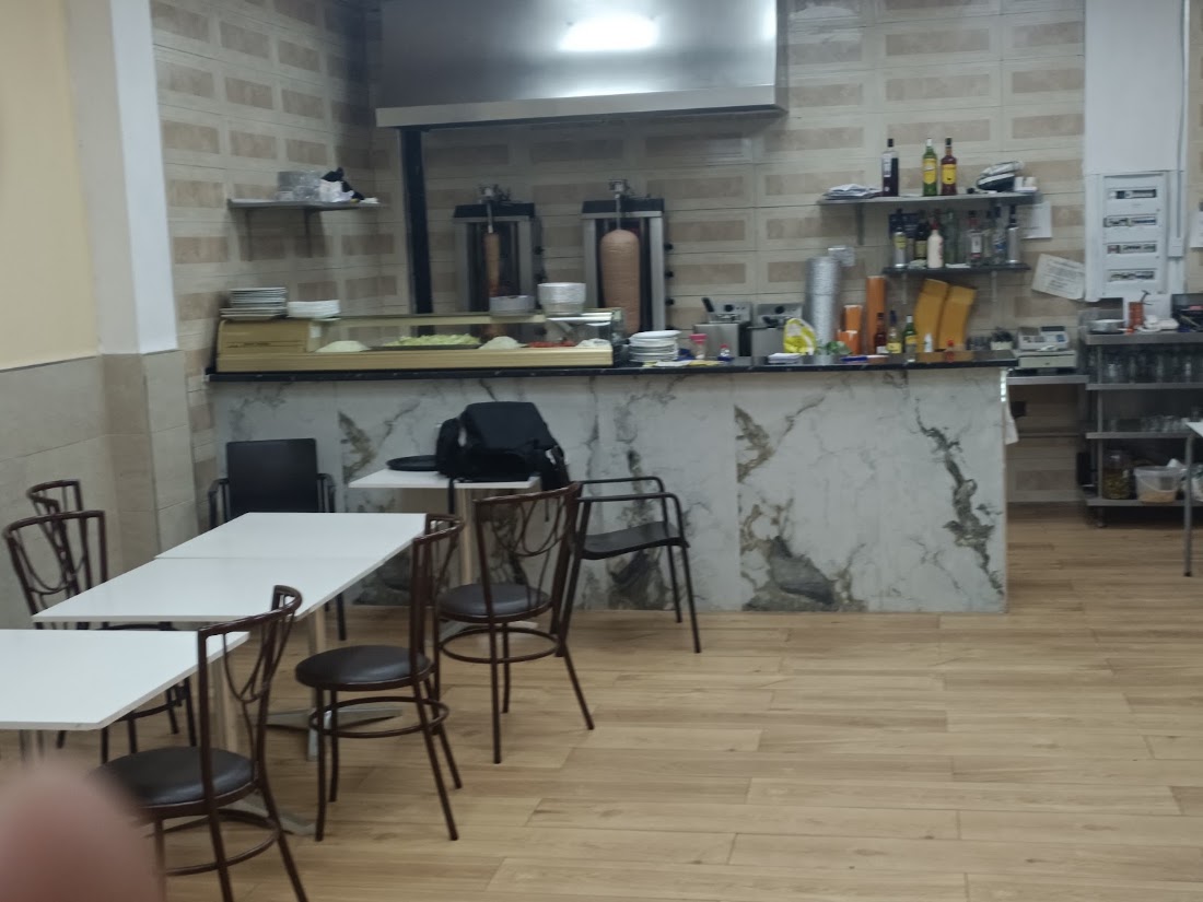 Interior del local con la barra de mármol y el kebab al fondo